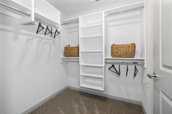 A walk in closet with white shelves and a white closet door